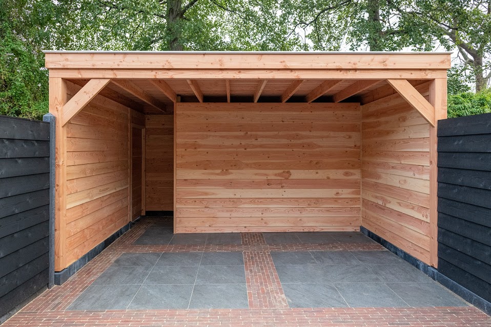 Houten overkapping van Douglas, met een vloer van tegels en een klinkerband, tussen zwarte schuttingen