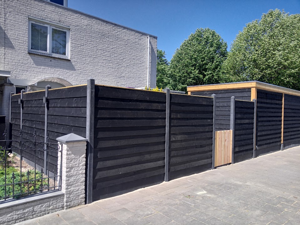 Zwarte schutting met poort langs de straat